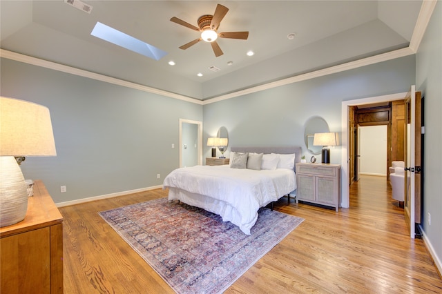 bedroom with light hardwood / wood-style floors, ceiling fan, crown molding, and a tray ceiling