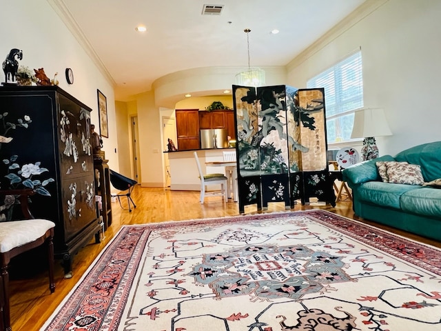 living room featuring an inviting chandelier, crown molding, and light hardwood / wood-style flooring