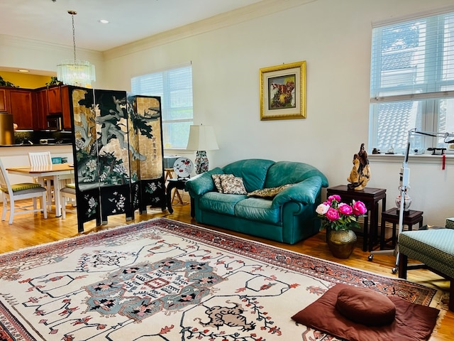 living room featuring a wealth of natural light, ornamental molding, and light wood-type flooring