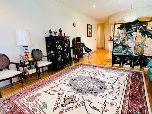 living room featuring hardwood / wood-style flooring, ornamental molding, and a chandelier