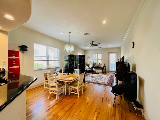 dining area with ceiling fan with notable chandelier, light hardwood / wood-style floors, and crown molding