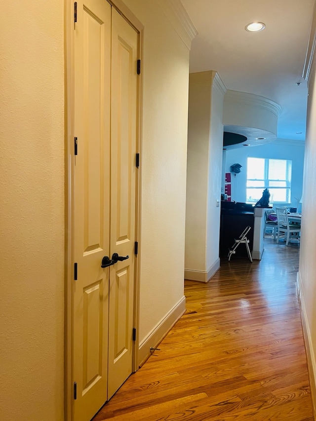 hallway with light hardwood / wood-style floors and crown molding