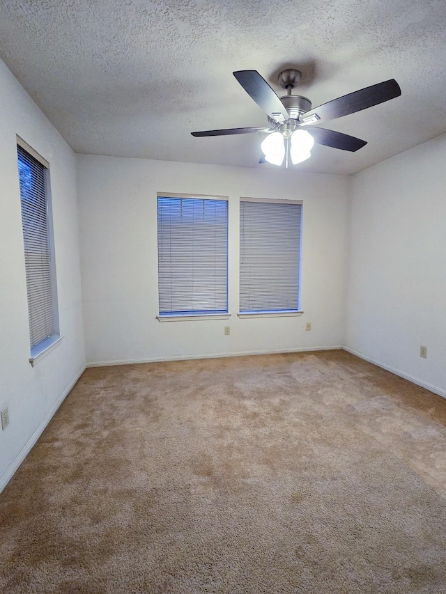 empty room with carpet flooring, ceiling fan, and a textured ceiling