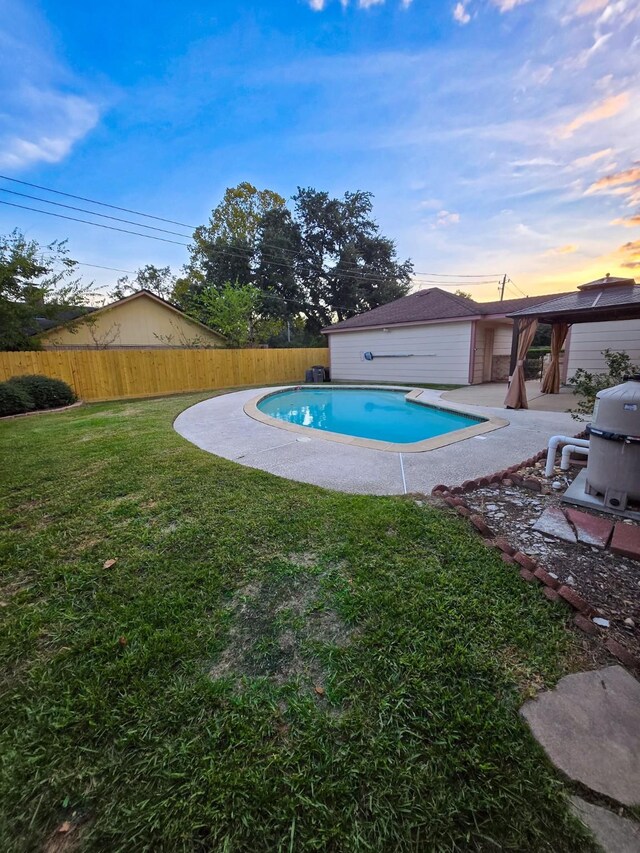 pool at dusk featuring a lawn and a patio area