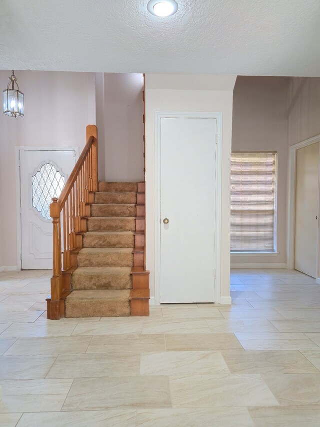 stairs featuring a textured ceiling and an inviting chandelier