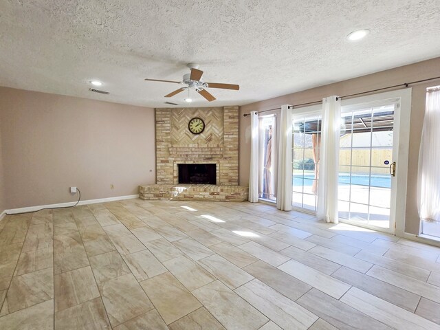 unfurnished living room featuring a textured ceiling, a brick fireplace, and ceiling fan