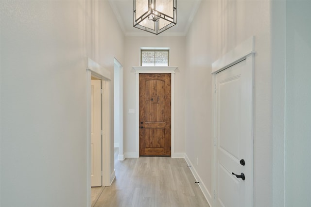 interior space with light hardwood / wood-style floors, ornamental molding, and an inviting chandelier