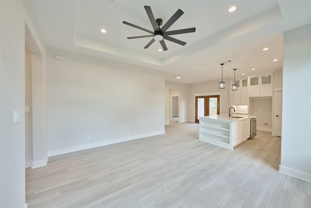 unfurnished living room featuring ceiling fan, light wood-type flooring, and sink