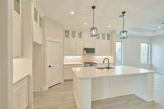 kitchen with sink, an island with sink, hanging light fixtures, and appliances with stainless steel finishes