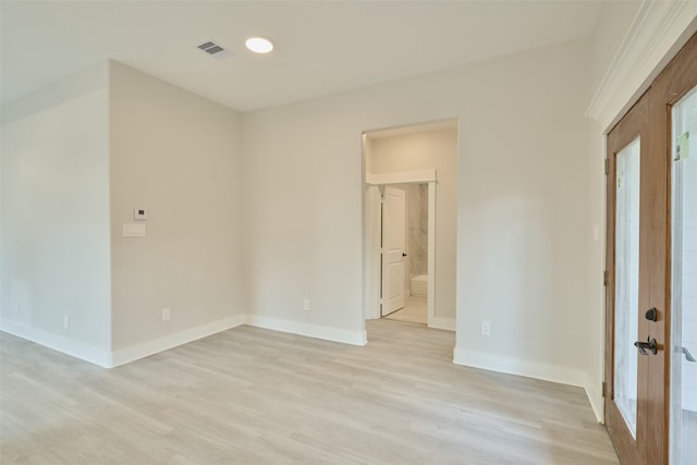 empty room featuring french doors and light hardwood / wood-style flooring