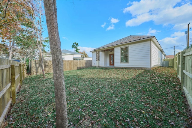 rear view of property featuring central AC and a lawn