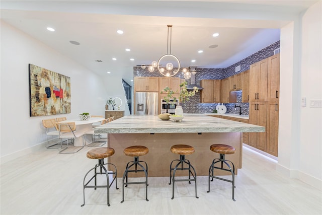 kitchen featuring appliances with stainless steel finishes, tasteful backsplash, a breakfast bar, decorative light fixtures, and a kitchen island