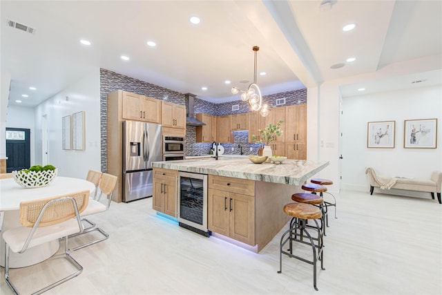 kitchen featuring a kitchen island with sink, wine cooler, decorative backsplash, stainless steel fridge, and decorative light fixtures