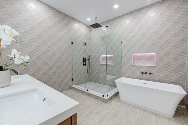 bathroom with hardwood / wood-style floors, vanity, independent shower and bath, and tile walls