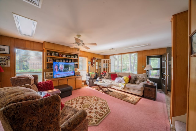 carpeted living room featuring ceiling fan and wooden walls