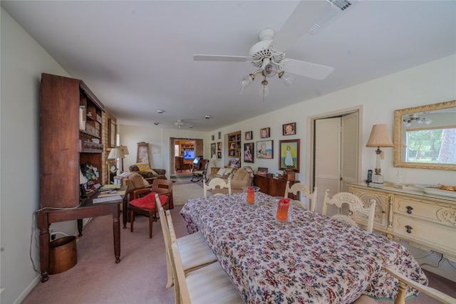 dining space with ceiling fan and light colored carpet