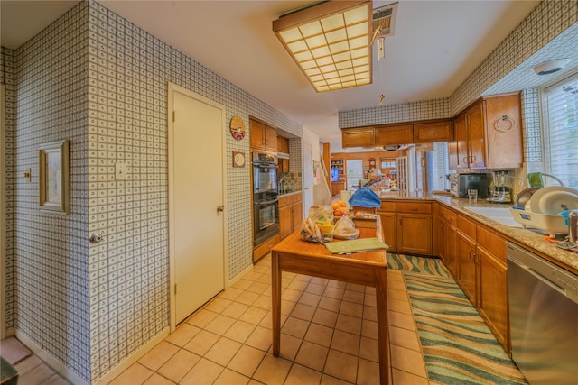 kitchen with black double oven, light tile patterned floors, stainless steel dishwasher, and sink