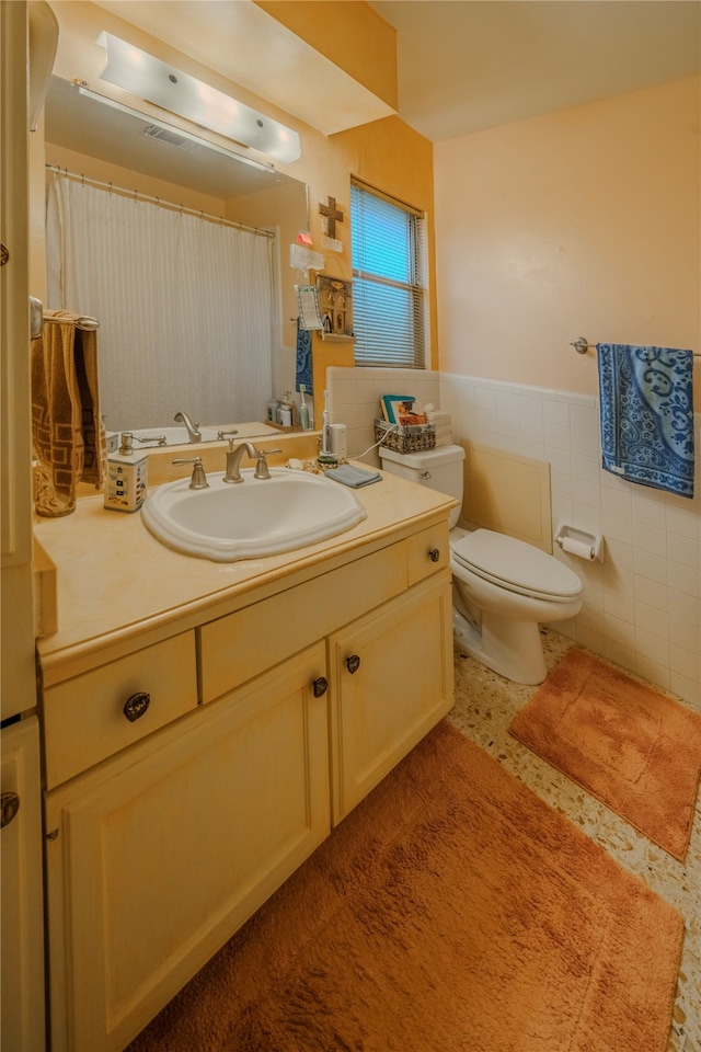 bathroom featuring vanity, toilet, and tile walls