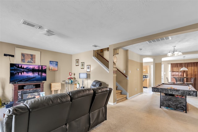 living room featuring light carpet, a chandelier, and a textured ceiling