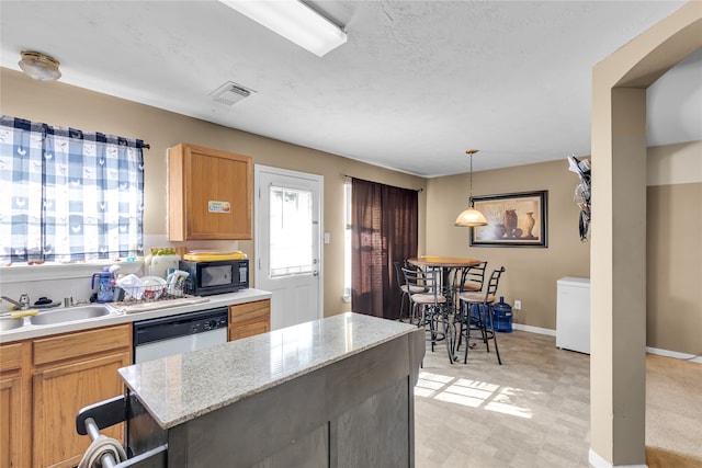 kitchen featuring light stone counters, a textured ceiling, sink, decorative light fixtures, and dishwasher