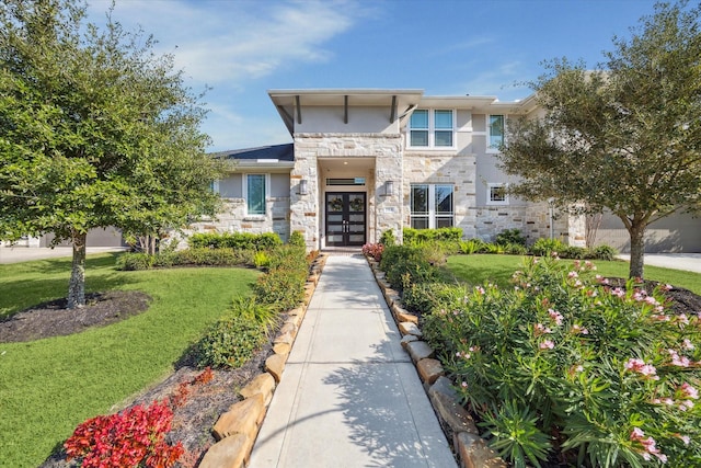 view of front of property with stone siding, a front yard, and stucco siding