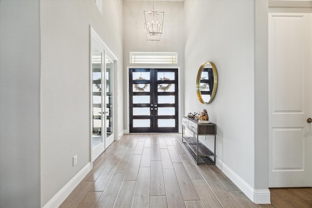 entryway featuring a towering ceiling, a chandelier, and french doors