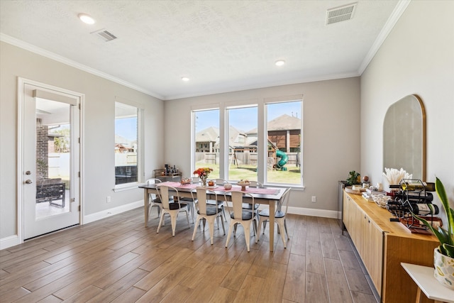 dining space with crown molding, hardwood / wood-style floors, and a textured ceiling