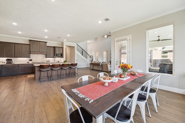 dining room with crown molding, sink, ceiling fan, and light hardwood / wood-style floors