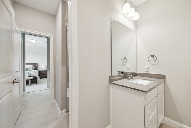 ensuite bathroom with baseboards, connected bathroom, vanity, and tile patterned floors