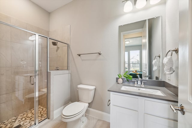 bathroom with a shower with door, vanity, and toilet