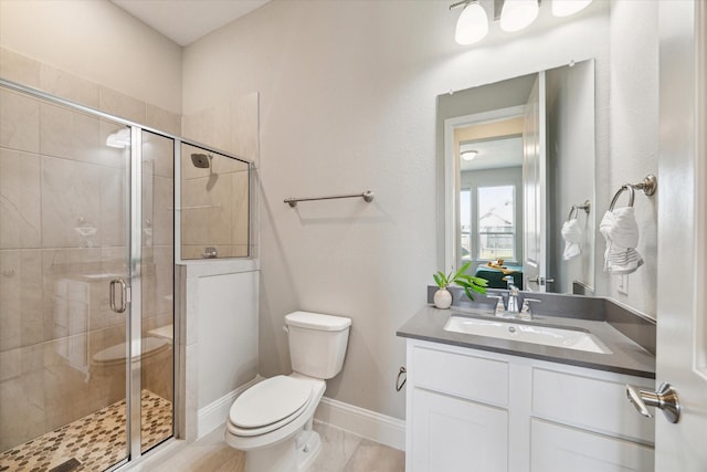 bathroom with toilet, a stall shower, baseboards, and vanity