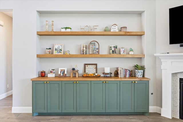 bar with built in shelves, a premium fireplace, and green cabinets