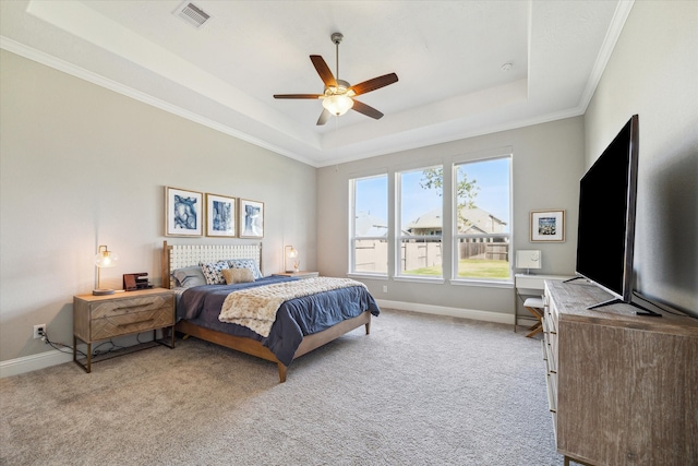 bedroom with ceiling fan, light colored carpet, ornamental molding, and a tray ceiling