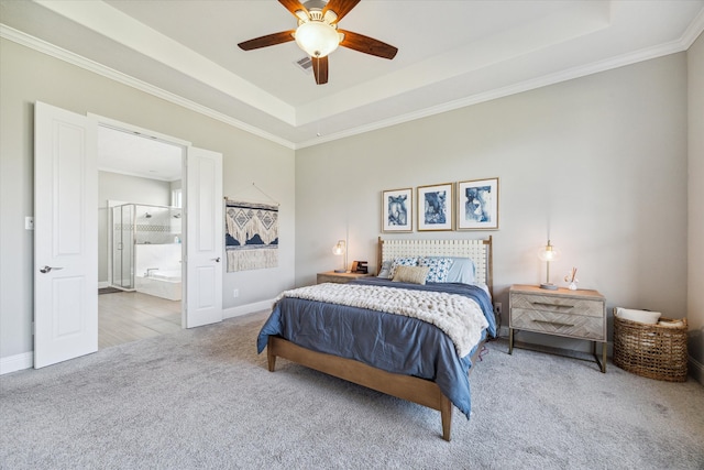 bedroom featuring a raised ceiling, crown molding, light carpet, and ensuite bath