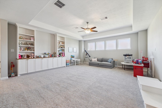 recreation room featuring a raised ceiling, carpet floors, and built in features