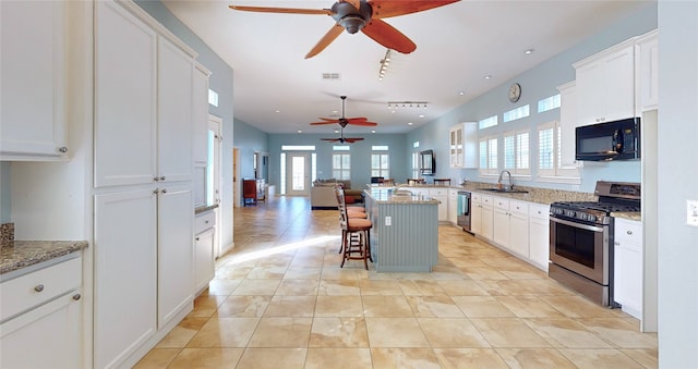 kitchen with white cabinetry, a kitchen bar, light stone countertops, and appliances with stainless steel finishes