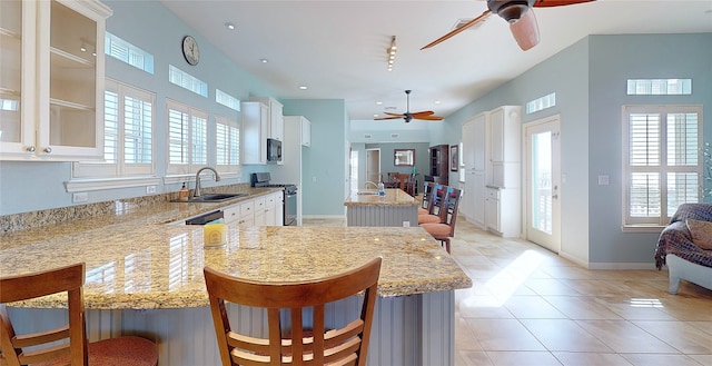 kitchen with sink, a breakfast bar area, stainless steel gas range, white cabinets, and kitchen peninsula