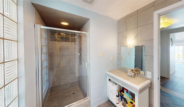 bathroom with an enclosed shower and tile walls