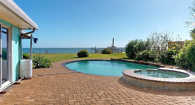 view of swimming pool with an in ground hot tub, a water view, and a yard