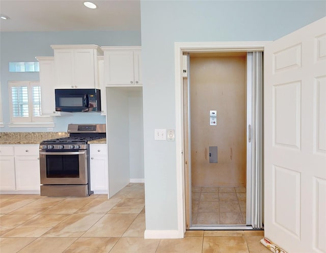 kitchen featuring white cabinets, light tile patterned floors, stainless steel gas range, and light stone counters