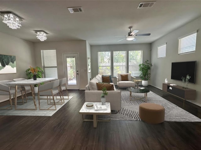 living room with ceiling fan with notable chandelier and dark hardwood / wood-style floors