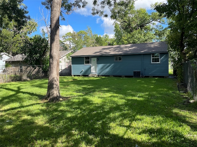 rear view of house with central air condition unit and a yard