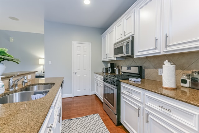 kitchen with white cabinets, appliances with stainless steel finishes, light hardwood / wood-style floors, and sink