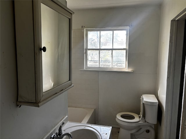 bathroom featuring a washtub, vanity, and toilet