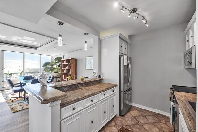 kitchen with pendant lighting, dark stone countertops, stainless steel appliances, white cabinets, and kitchen peninsula