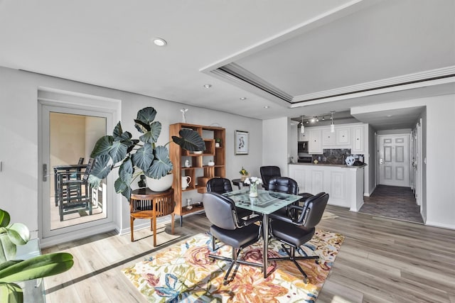 dining room with light hardwood / wood-style flooring and a raised ceiling