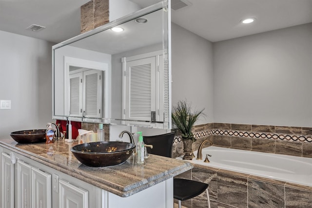 bathroom with vanity and a relaxing tiled tub