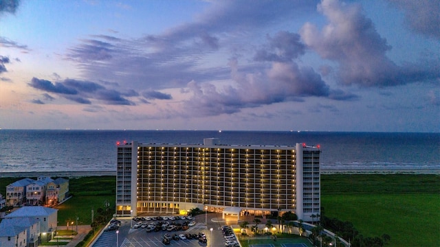 aerial view at dusk with a water view and a view of the beach