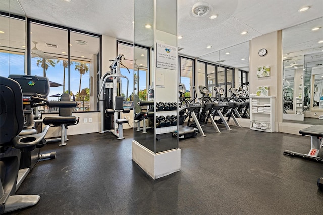 gym with floor to ceiling windows and a textured ceiling