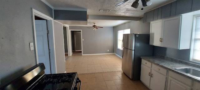 kitchen featuring stainless steel fridge, a textured ceiling, light tile patterned floors, black gas stove, and white cabinetry